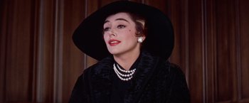 Movie still from “Les Girls” (1957), directed by George Cukor – A woman wearing a black hat and a black coat; Close Up shot, Low angle