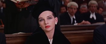 Movie still from “Les Girls” (1957), directed by George Cukor – A woman in a black dress and a black hat; Close Up shot, Over the shoulder angle
