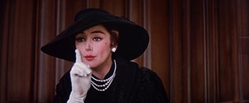 Movie still from “Les Girls” (1957), directed by George Cukor – A woman in a black hat and white gloves; Close Up shot, Over the shoulder angle