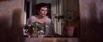 Movie still from “Les Girls” (1957), directed by George Cukor – A woman standing in front of potted plants; Close Up shot, Low angle