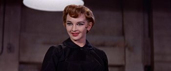 Movie still from “Les Girls” (1957), directed by George Cukor – A woman in a black dress smiling for the camera; Close Up shot, Low angle