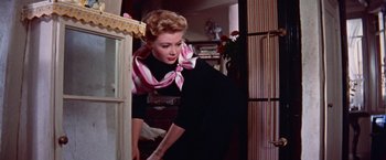 Movie still from “Les Girls” (1957), directed by George Cukor – A woman in a black dress and a pink and white striped scarf; Medium shot, Low angle