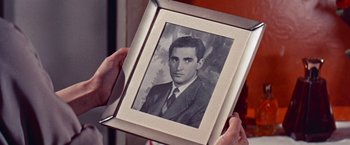 Movie still from “Les Girls” (1957), directed by George Cukor – A man holding a picture of himself in a suit and tie; Extreme Close Up shot, Over the shoulder angle