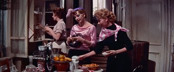 Movie still from “Les Girls” (1957), directed by George Cukor – A group of women standing next to each other at a table; Medium shot, Low angle