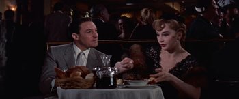 Movie still from “Les Girls” (1957), directed by George Cukor – A man and a woman sitting at a dinner table; Medium shot, Over the shoulder angle