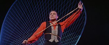 Movie still from “Les Girls” (1957), directed by George Cukor – A man in a red shirt and black vest holding onto some ropes; Medium shot, Low angle