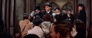 Movie still from “Les Girls” (1957), directed by George Cukor – A man in a crowd of people; Medium shot, Over the shoulder angle