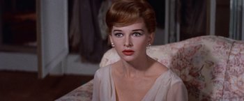 Movie still from “Les Girls” (1957), directed by George Cukor – A beautiful woman sitting on a chair in a room; Close Up shot, Over the shoulder angle
