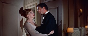 Movie still from “Les Girls” (1957), directed by George Cukor – A man and a woman standing next to each other in front of a door; Medium shot, Low angle