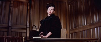 Movie still from “Les Girls” (1957), directed by George Cukor – A woman in a black coat and a black hat; Medium shot, Low angle