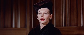 Movie still from “Les Girls” (1957), directed by George Cukor – A woman wearing a black hat and a black coat; Close Up shot, Low angle