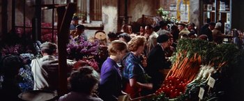Movie still from “Les Girls” (1957), directed by George Cukor – A group of people standing around a flower market; Wide shot, High angle