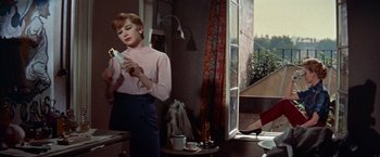 Movie still from “Les Girls” (1957), directed by George Cukor – A woman standing in front of a window holding a phone; Medium shot, Low angle