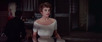 Movie still from “Les Girls” (1957), directed by George Cukor – A woman in a white dress sitting at a table in front of a mirror; Medium shot, Low angle