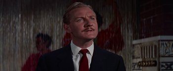 Movie still from “Les Girls” (1957), directed by George Cukor – A person wearing a suit and tie; Close Up shot, Low angle