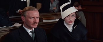 Movie still from “Les Girls” (1957), directed by George Cukor – A man and a woman sitting next to each other in a courtroom; Close Up shot, Over the shoulder angle