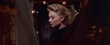 Movie still from “Les Girls” (1957), directed by George Cukor – A woman in a black shirt looking at her reflection in a mirror; Close Up shot, Low angle
