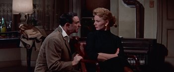 Movie still from “Les Girls” (1957), directed by George Cukor – A man and a woman sitting on a chair; Medium shot, Low angle