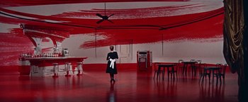 Movie still from “Les Girls” (1957), directed by George Cukor – A woman standing in front of a room with red walls; Extreme Wide shot, Low angle