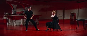 Movie still from “Les Girls” (1957), directed by George Cukor – A man and a woman in a black dress on a red floor; Wide shot, Low angle