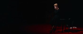 Movie still from “Les Girls” (1957), directed by George Cukor – A woman in a black dress sitting on the ground; Wide shot, High angle