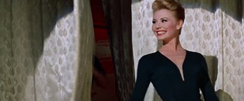 Movie still from “Les Girls” (1957), directed by George Cukor – A woman in a black dress standing in front of a window; Medium shot, Low angle