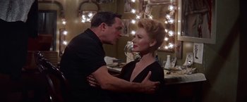 Movie still from “Les Girls” (1957), directed by George Cukor – A man and a woman are standing in front of a mirror; Medium shot, Low angle