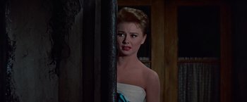 Movie still from “Les Girls” (1957), directed by George Cukor – A woman in a strapless white dress standing in front of a door; Close Up shot, Low angle