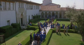Movie still from “Less Than Zero” (1987), directed by Marek Kanievska – A group of people standing on a walkway in front of a building; Extreme Wide shot, High angle