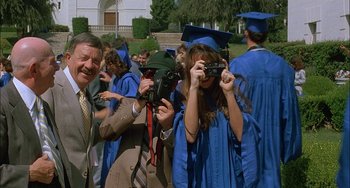 Movie still from “Less Than Zero” (1987), directed by Marek Kanievska – A group of people taking pictures of a graduation ceremony; Medium shot, Low angle