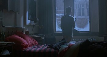 Movie still from “Less Than Zero” (1987), directed by Marek Kanievska – A man standing in a bedroom looking out a window; Wide shot, Over the shoulder angle