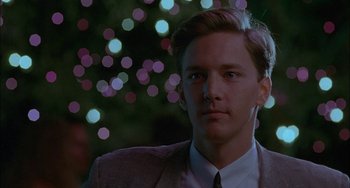 Movie still from “Less Than Zero” (1987), directed by Marek Kanievska – A man in a suit and tie in front of a christmas tree; Close Up shot, Over the shoulder angle