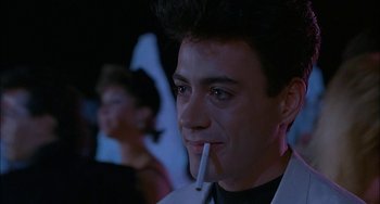 Movie still from “Less Than Zero” (1987), directed by Marek Kanievska – A man with a cigarette in his mouth; Close Up shot, Over the shoulder angle