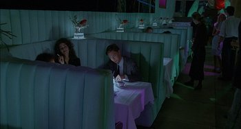 Movie still from “Less Than Zero” (1987), directed by Marek Kanievska – A man and a woman sitting at a booth in a restaurant; Wide shot, High angle