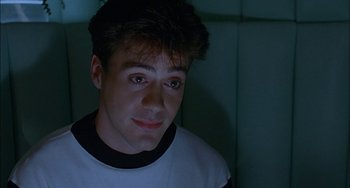 Movie still from “Less Than Zero” (1987), directed by Marek Kanievska – A young man is looking into the camera; Close Up shot, Over the shoulder angle
