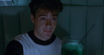 Movie still from “Less Than Zero” (1987), directed by Marek Kanievska – A young man looking at a jar of green liquid; Close Up shot, Over the shoulder angle