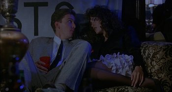 Movie still from “Less Than Zero” (1987), directed by Marek Kanievska – A man and a woman sitting next to each other on a couch; Medium shot, Low angle