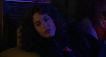 Movie still from “Less Than Zero” (1987), directed by Marek Kanievska – A woman with long curly hair laying on a couch; Close Up shot, High angle