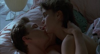 Movie still from “Less Than Zero” (1987), directed by Marek Kanievska – A man and a woman laying in a bed kissing; Close Up shot, Overhead angle