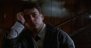 Movie still from “Less Than Zero” (1987), directed by Marek Kanievska – A man with a tie is sitting in a dark room; Close Up shot, Low angle