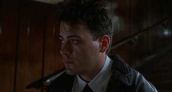 Movie still from “Less Than Zero” (1987), directed by Marek Kanievska – A person wearing a suit and tie; Close Up shot, Low angle