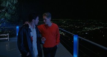 Movie still from “Less Than Zero” (1987), directed by Marek Kanievska – Two young men standing next to each other at night; Medium shot, Over the shoulder angle