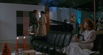Movie still from “Less Than Zero” (1987), directed by Marek Kanievska – A group of people standing in a living room next to a piano; Wide shot, High angle