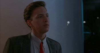 Movie still from “Less Than Zero” (1987), directed by Marek Kanievska – A man in a suit and red tie looking to his left; Close Up shot, Low angle
