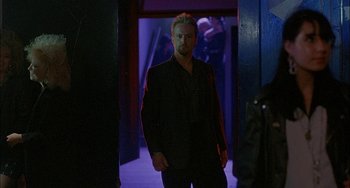 Movie still from “Less Than Zero” (1987), directed by Marek Kanievska – A man in a suit standing in a dark room; Medium shot, Over the shoulder angle