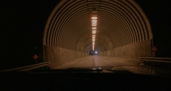 Movie still from “Less Than Zero” (1987), directed by Marek Kanievska – A car driving down a road through a tunnel; Extreme Wide shot, High angle