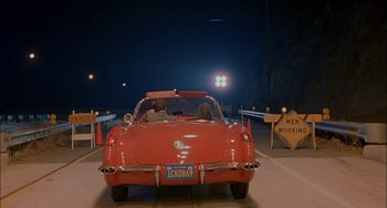 Movie still from “Less Than Zero” (1987), directed by Marek Kanievska – Two people in the back seat of a red car; Wide shot, High angle
