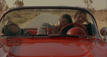Movie still from “Less Than Zero” (1987), directed by Marek Kanievska – Two young men in a red car driving down a road; Medium shot, Over the shoulder angle