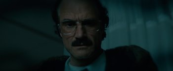 Movie still from “Let Me In” (2010), directed by Matt Reeves – A person wearing a suit and glasses; Close Up shot, Low angle