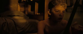 Movie still from “Let Me In” (2010), directed by Matt Reeves – A young man sitting in a dark room; Close Up shot, High angle